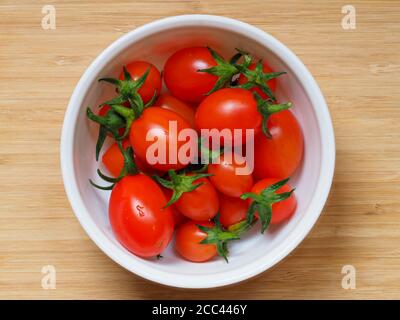 Frisch gepflückte hellrote selbstangebaute Tomaten, Sorte Tutti Frutti, in einer kleinen Schüssel Stockfoto