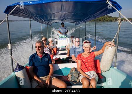 Westliche Touristen auf Exkursion im Touristenboot auf dem Dulce Fluss von der Stadt Rio Dulce zur Mündung in Livingston, Izabal Department, Guatemala Stockfoto