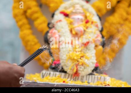 Hände Räucherstäbchen oder Agarbatti halten oder anbieten Von herrn vinayaka oder Ganesha während des Betens oder der Anbetung während festspielzeremonie Stockfoto