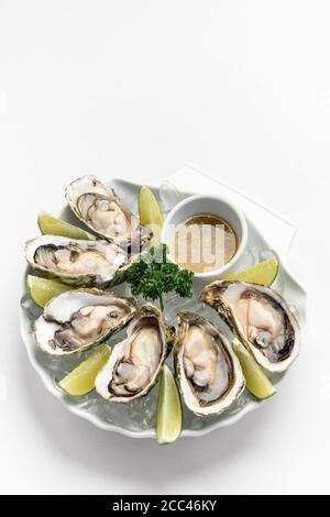 Sechs frische Austern mit Limettenkeilen und Thai-piky Chili Soße Stockfoto