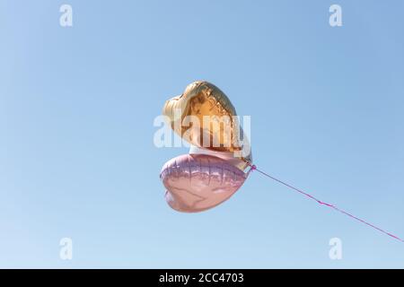 Herzförmige Luftballons fliegen in den Himmel an einer Schnur befestigt Stockfoto