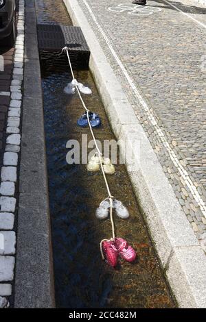 Ein kleiner wassergefüllter Runnel oder formalisierte Rillen genannt Freiburg Bächle mit bunten Wasserschuhen im Inneren mit kleinen Seil in Freiburg verbunden. Stockfoto