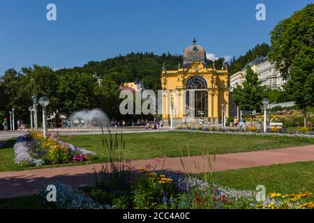 Marianske Lazne / Tschechien - August 11 2020: Blick auf die Maxim Gorki Kolonnade mit gelbem Gebäude, Wasserbrunnen, grüner Wiese und Blumen. Stockfoto