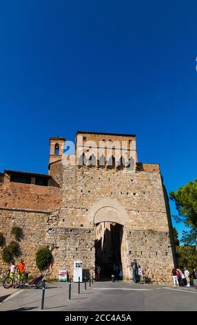 Schönes Porträt des Tores San Giovanni, der Eingang der mittelalterlichen Stadt San Gimignano in der Toskana, Italien. Ein Kirchturm aus einem... Stockfoto