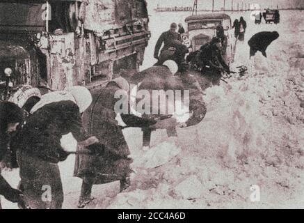 Die Nazis nutzen die Zwangsarbeit sowjetischer Zivilisten (Frauen und alte Menschen), um Straßen aus dem Schnee zu räumen, um einen Armeekonvoi zu durchfahren. Stockfoto