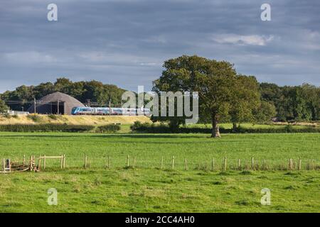 Erster TransPennine Express CAF Klasse 397 Elektrozug vorbei an der Landschaft an der Westküste Hauptlinie in Lancashire Stockfoto