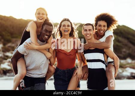 Gruppe von multiethnischen Freunden auf einem Urlaub genießen zusammen. Freunde mit Spaß Piggy Reiten in einem Urlaub. Stockfoto