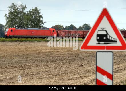 18. August 2020, Brandenburg, Niedergörsdorf/ OT Oehna: Ein Güterzug fährt an einem eingezäunten Bahnübergang neben einem geernteten Feld. Foto: Soeren Sache/dpa-Zentralbild/ZB Stockfoto