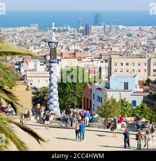 Barcelona, Spanien.  Parc Güell.  Gran Plaça Rundschreiben.  Central Plaza.  Barcelona-Stadtansicht im Hintergrund.  Park Güell wurde von Antoni Gaudi entworfen. Stockfoto