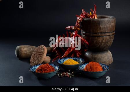 Traditionelle getrocknete Kräuter und Gewürze. Holzpresse und Stößel. Stillleben auf dunklem Hintergrund. Stockfoto