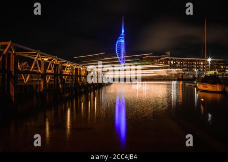 Der Spinnaker Turm in gunwharf Kais beleuchtet in der Nacht von Old Portsmouth, mit den leichten Wegen einer vorbeifahrenden wightlink Fähre Stockfoto