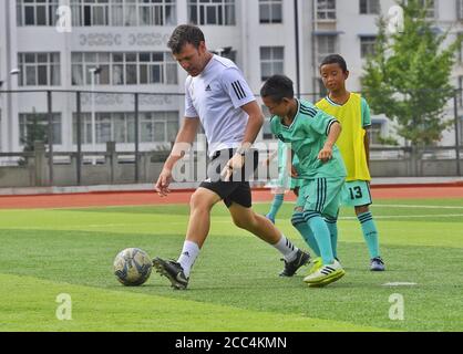 (200818) -- ZHAOJUE, 18. August 2020 (Xinhua) -- Foto vom 11. August 2020 zeigt Kinder aus Zhaojue Real Madrid, die mit Javier Moros Barrera (L) auf dem Lamo-Fußballplatz im Bezirk Zhaojue, südwestlich der chinesischen Provinz Sichuan, Fußball spielen. Ein 30-jähriger UEFA A A A LEVEL Trainer aus Zaragoza, Spanien, trainiert seit dem 13. Juli 2020 eine Fußballmannschaft aus 15 Jungen aus dem Bezirk Zhaojue und ländlichen Dörfern in der Nähe des Bezirks in der chinesischen Provinz Sichuan. Das Fußballteam namens Zhaojue Real Madrid Team ist Teil eines Trainingsprojekts, das im vergangenen Oktober ins Leben gerufen wurde Stockfoto