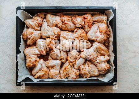 Roh mariniertes Hühnerfleisch Flügel in einer Marinade auf einem Backblech.Kochen Huhn mit Gewürzen im Ofen. Flach liegend Stockfoto