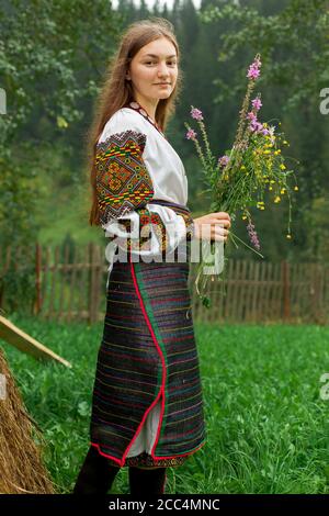 Mädchen mit lockeren Haaren mit einem Blumenstrauß steht Bei einem Heuhaufen Stockfoto