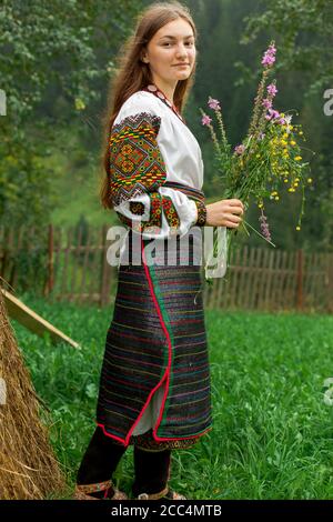 Mädchen mit lockeren Haaren mit einem Blumenstrauß steht Bei einem Heuhaufen Stockfoto