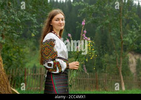 Mädchen mit lockeren Haaren mit einem Blumenstrauß steht Bei einem Heuhaufen Stockfoto