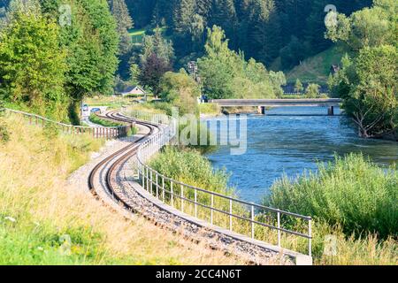 Kurvende Eisenbahn entlang eines Flusses schlängelt sich durch ein Tal in den Alpen Stockfoto