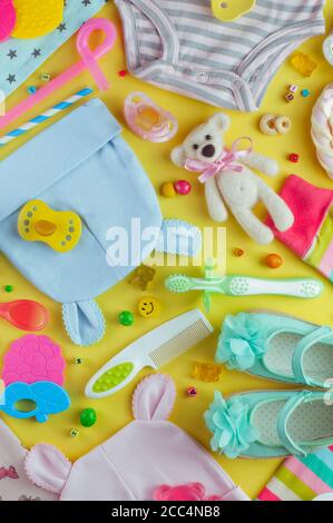 Babykleidung, Accessoires, Spielzeug und Süßigkeiten auf dem gelben Hintergrund Stockfoto