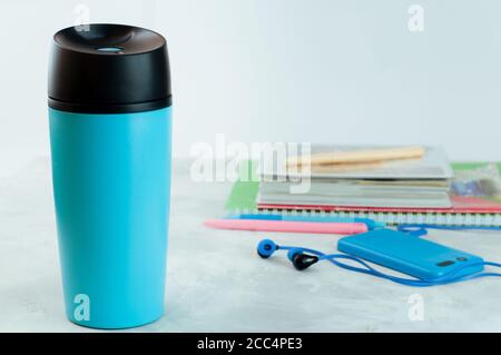 Blaue Kaffeetasse zum Mitnehmen in der Nähe von Notebooks und Mobiltelefonen Stockfoto