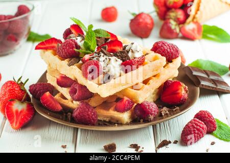 Belgische Waffeln mit Himbeere, Erdbeere, Schlagsahne und geriebener Schokolade Stockfoto