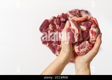 Gehacktes rohes Schweinefleisch in den Händen. Eine Frau hält fein geschnittenes Schweinefleisch ein Zeichen weißen Hintergrund. Feines Schweinefleisch Konzept. Stockfoto