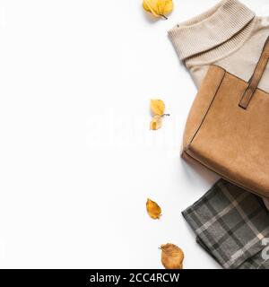 Herbstkleidung Set mit Herbstblättern auf weiß, Draufsicht, Kopierraum. Stilvolles und gemütliches, saisonales Damenoutfit. Stockfoto