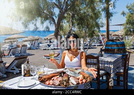 Schöne junge Frau trinkt Wein in einem Fischrestaurant auf Der Strand Stockfoto