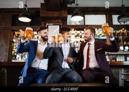 Fröhliche alte Freunde, die Spaß haben und Bier am Barschalter in der Kneipe trinken. Stockfoto