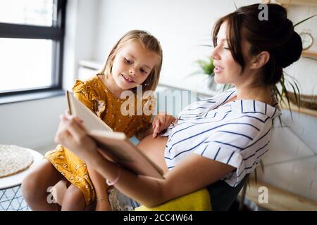 Mädchen und ihre schwangere Mutter Lesung gemeinsam buchen. Zeit mit der Familie Stockfoto