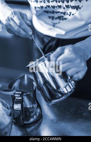 Hände der weiblichen Barista Gießen gedämpfte Milch aus Krug zu Cappuccinotasse Stockfoto