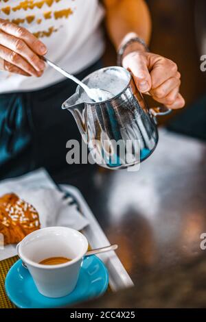 Hände der weiblichen Barista Gießen gedämpfte Milch aus Krug zu Cappuccinotasse Stockfoto