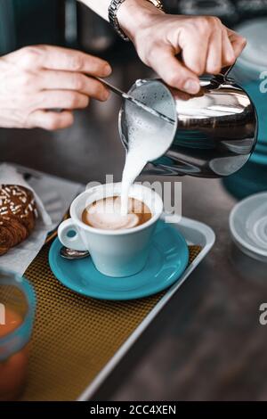 Hände der weiblichen Barista Gießen gedämpfte Milch aus Krug zu Cappuccinotasse Stockfoto