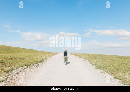 Junge weibliche Natur Entdecker zu Fuß auf einer Schotterstraße in Sommerzeit Stockfoto