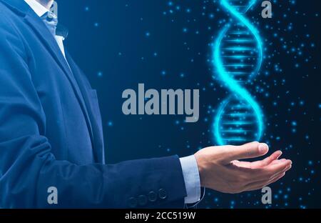 Junger Mann im Business-Anzug mit glühender DNA-Spirale in den Händen vor dunklem Hintergrund, Collage Stockfoto