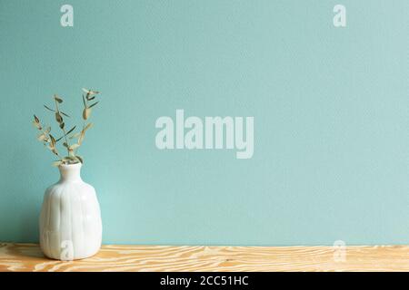 Vase aus Eukalyptusblättern auf Holztisch mit grünem Hintergrund Stockfoto