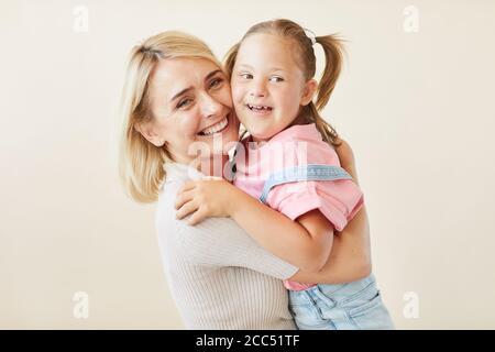 Portrait einer glücklichen Mutter, die ihre Tochter mit Down-Syndrom umarmt Vor dem weißen Hintergrund Stockfoto