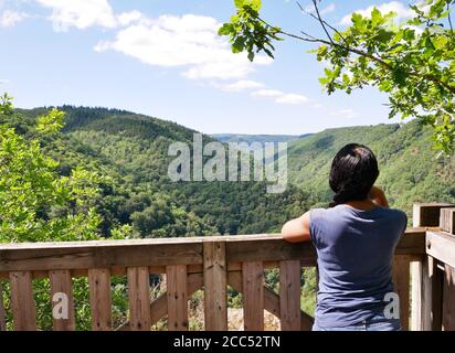 Eine afro-asiatische Frau von hinten betrachtet bewundert die Berglandschaft. Stockfoto