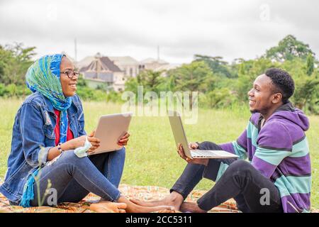 Flacher Fokus von zwei jungen afrikanischen Menschen mit Laptops an Ein Park bei Tageslicht Stockfoto
