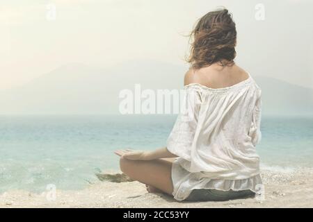 Die meditierende Frau macht Yoga-Übungen vor dem Ozean Stockfoto