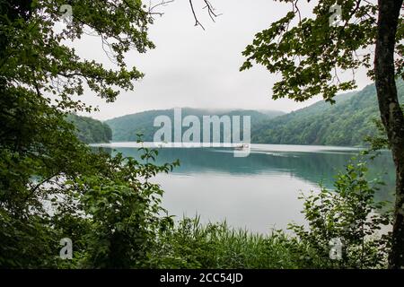 Blick über den Kozjak See mit einem Touristenboot im Hintergrund, Plitvicer Seen, Kroatien Stockfoto