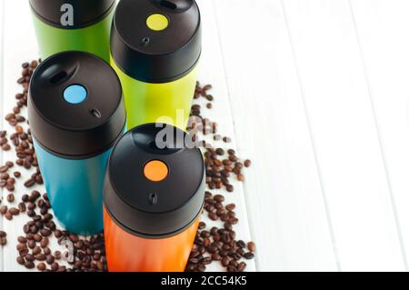 Farbe Thermoskannen Tassen in der Nähe Kaffeebohnen auf dem weißen Hintergrund Stockfoto