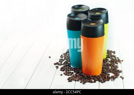 Farbe Thermoskannen Tassen neben Kaffeebohnen auf dem weißen Holz Tabelle Stockfoto