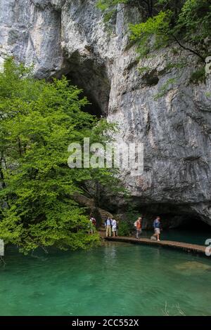 Touristen, die auf einem erhöhten Weg, durch eine große Höhle, auf Plitvicer Seen, Kroatien Stockfoto