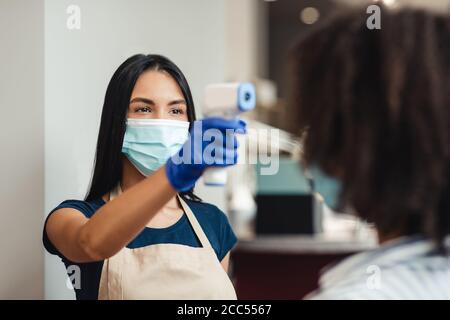 Schönheitssalon Arbeiter Überprüfung Client Körpertemperatur vor Verfahren Stockfoto