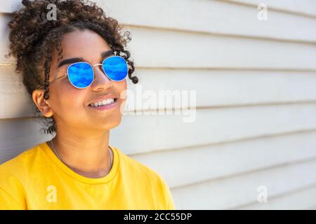 Mädchen Teenager Teenager gemischt Rasse biracial afroamerikanischen weiblich jung Frau trägt blaue Sonnenbrille lächelt mit perfekten Zähnen im Urlaub Im Sommer so Stockfoto