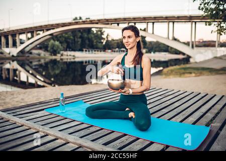 Sportlerin meditiert mit tibetischer Glocke Stockfoto