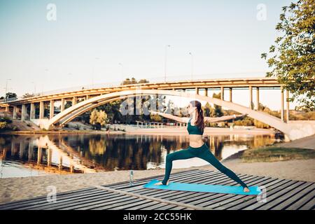 Sportlerin macht Yoga auf hölzerner Plattform Stockfoto