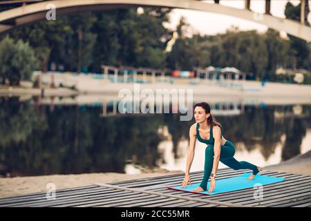 Sportlerin macht Yoga auf hölzerner Plattform Stockfoto