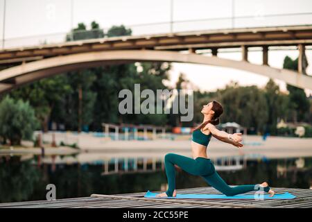 Sportlerin macht Yoga auf hölzerner Plattform Stockfoto