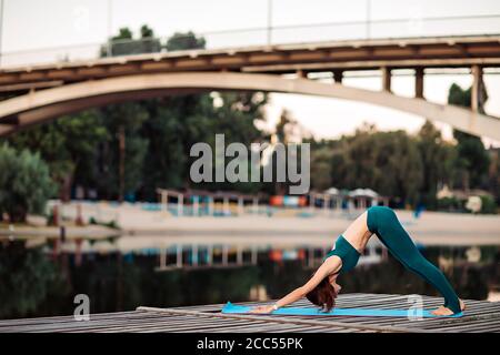 Sportlerin macht Yoga auf hölzerner Plattform Stockfoto